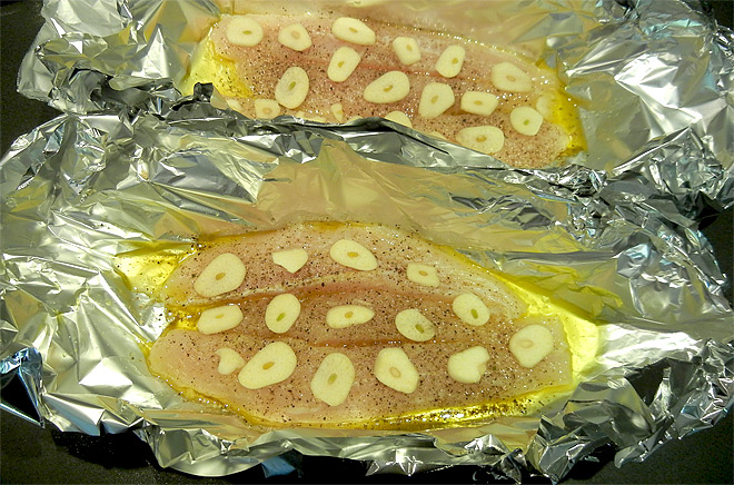 Fischfilet mit Knoblauch in Alufolie vor dem Grillen